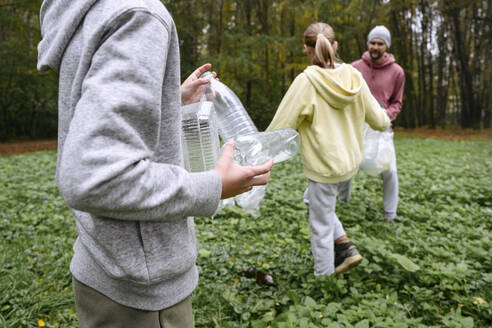 Vater mit Kindern beim Müllsammeln auf der Wiese - EYAF02201