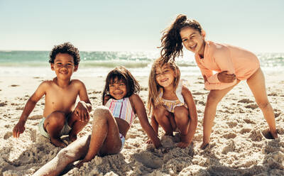 Spain, Gijon, group picture of three little girls sitting at rocky coast  stock photo