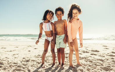 Glückliche junge Freunde, die fröhlich lachen, während sie zusammen am Strand stehen. Gruppe von entzückenden kleinen Kindern, die während der Sommerferien zusammen Spaß haben. - JLPSF09456