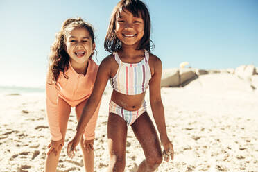 Zwei glückliche kleine Kinder, die in die Kamera lächeln, während sie mit Sand bedeckt sind. - JLPSF09460