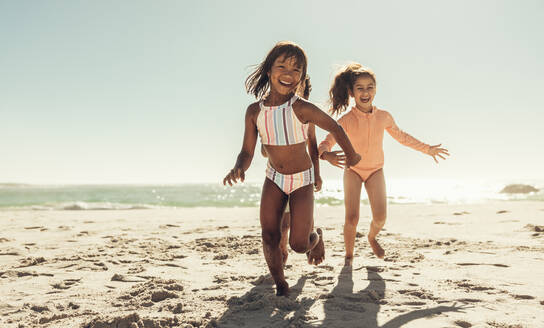 Aufgeregte Kinder lachen fröhlich, während sie am Strand herumlaufen. Gruppe von glücklichen Kindern, die Spaß haben, während sie am Strand spielen. Bezaubernde kleine Kinder, die ihre Sommerferien genießen. - JLPSF09465