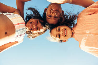 Low angle view of cheerful kids smiling happily while covered in beach sand. Group of adorable little children having fun together during summer vacation. - JLPSF09472