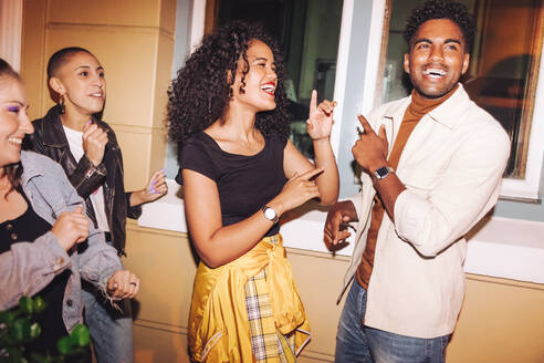 Eine Gruppe fröhlicher junger Freunde singt und tanzt im Freien zu ihrem Lieblingslied. Multikulturelle junge Leute, die sich an einem Wochenendabend amüsieren und zusammen abhängen. - JLPSF09538