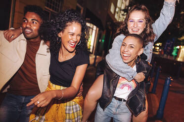 Young people laughing and living their best lives in the city. Happy young people having fun while hanging out together at night. Vibrant friends spending their weekend together. - JLPSF09547