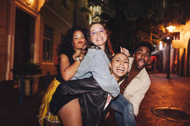 Group of vibrant friends looking at the camera cheerfully. Multicultural young people having a good time while hanging out together outdoors in the city. Friends enjoying a great weekend together. - JLPSF09557