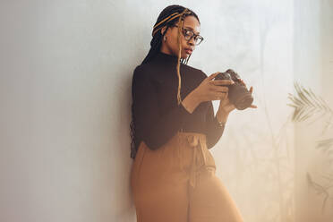 Preparing to do some camera work. Artistic female photographer setting up her dslr camera while standing in her home office.. Creative female freelancer getting ready for a photo shoot. - JLPSF09694