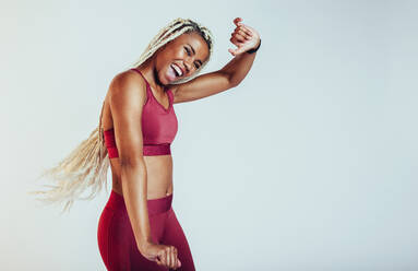 Porträt einer glücklichen Fitness-Frau, die vor Freude tanzt. Afrikanischer Athlet, der Spaß am Tanzen hat, auf weißem Hintergrund. - JLPSF09771