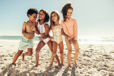 Multiethnische Kinder lachen fröhlich, während sie zusammen am Strand spielen. Gruppe von glücklichen jungen Freunden, die während der Sommerferien zusammen Spaß haben. - JLPSF09965