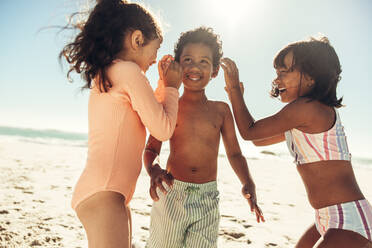 Fröhliche kleine Kinder, die fröhlich lachen, während sie zusammen am Strand spielen. Gruppe von liebenswerten kleinen Kindern, die Spaß haben und ihre Sommerferien genießen. - JLPSF09973