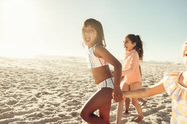 Bezaubernde kleine Kinder, die zusammen am Strand rennen und Spaß haben. Eine Gruppe glücklicher kleiner Kinder, die ihren Sommerurlaub an einem sonnigen Strand genießen. - JLPSF09998