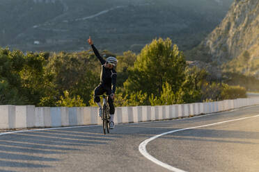 Radfahrer mit erhobener Hand beim Radfahren an der Costa Blanca in Alicante, Spanien - AMNF00014