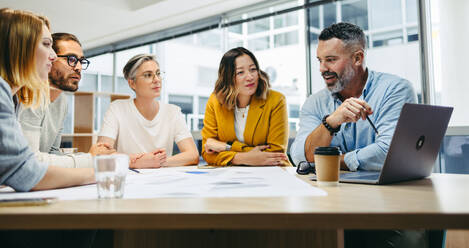 Eine Gruppe multikultureller Designer diskutiert während einer Besprechung im Büro. Ein Team innovativer Geschäftsleute tauscht kreative Ideen aus, während sie an einem neuen Projekt arbeiten. - JLPSF10154