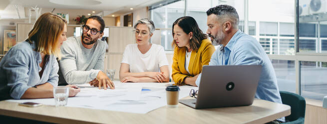 Multikulturelle Designer tauschen bei einem Treffen in einem modernen Büro kreative Ideen aus. Eine Gruppe innovativer Geschäftsleute diskutiert während der Arbeit an einem neuen Projekt. - JLPSF10156