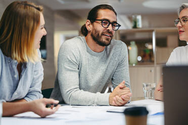 Kreative Geschäftsleute diskutieren während einer Besprechung in einem modernen Büro. Eine Gruppe innovativer Design-Profis tauscht Ideen aus, während sie an einem neuen Projekt arbeiten. - JLPSF10158