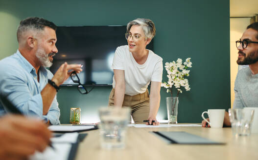 Reife Geschäftsleute bei einer Diskussion in einem Sitzungssaal. Eine Gruppe kreativer Geschäftskollegen tauscht während einer Sitzung an einem modernen Arbeitsplatz Ideen aus. - JLPSF10181