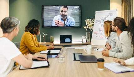 Eine Gruppe innovativer Geschäftsleute hält eine Videokonferenz in einem Sitzungssaal ab. Ein Team von kreativen Geschäftsleuten arbeitet an einem Projekt für erneuerbare Energien. - JLPSF10186