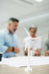 Group of creative engineers working with 3D wind turbine models in a modern office. Team of innovative businesspeople brainstorming while working on a renewable energy project. - JLPSF10197