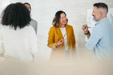 Fröhlich lachende Geschäftsleute bei einer Diskussion über ein kreatives Büro. Eine Gruppe multikultureller Designfachleute arbeitet gemeinsam an einem neuen innovativen Projekt. - JLPSF10208