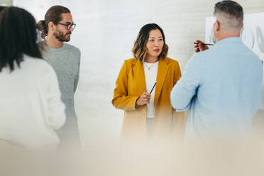 Diverse design professionals sharing innovative ideas during a meeting in a modern office. Team of multicultural businesspeople collaborating on a new creative project. - JLPSF10209