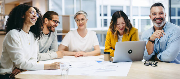 Fröhlich lächelnde Design-Profis bei einer Besprechung in einem modernen Büro. Eine Gruppe innovativer Geschäftsleute tauscht kreative Ideen aus, während sie an einem neuen Projekt arbeiten. - JLPSF10228