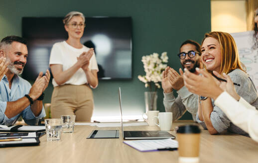 Erfolgreiche Geschäftsleute applaudieren ihren Kollegen während einer Vorstandssitzung. Eine Gruppe fröhlicher Geschäftsleute feiert ihre Erfolge in einem modernen Büro. - JLPSF10232