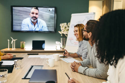 Moderne Geschäftsleute bei einer Videokonferenz in einem Sitzungssaal. Eine Gruppe innovativer Geschäftsleute tauscht kreative Ideen aus, während sie an einem neuen Projekt arbeiten. - JLPSF10240