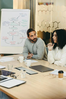 Kreative Geschäftsleute, die an einem modernen Arbeitsplatz an einer Vorstandssitzung teilnehmen. Zwei junge Geschäftsleute diskutieren während der Arbeit an einem neuen Projekt. - JLPSF10244
