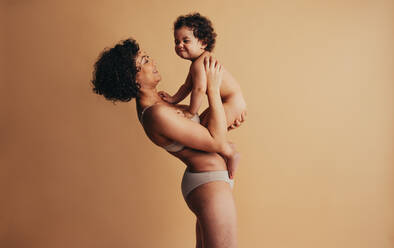 Woman holding her baby up. Real body of a healthy mother. - JLPSF10275