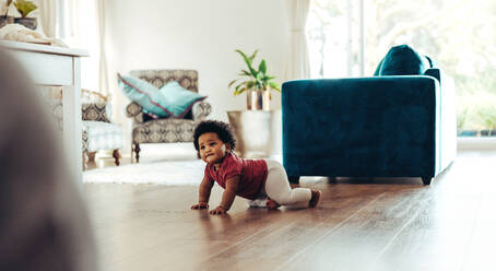 Cute baby crawling on floor. African baby moving inside living room. - JLPSF10317