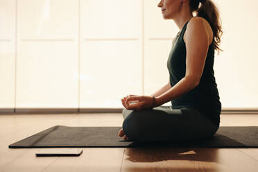 Ältere Frau meditiert, während sie in einer einfachen Haltung sitzt. Ältere Frau, die eine Atemübung während einer Hatha-Yoga-Sitzung macht. Frau, die ein gesundes Trainingsprogramm zu Hause absolviert. - JLPSF10353