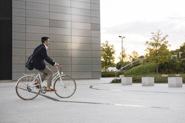 Geschäftsmann auf dem Fahrrad vor einem Bürogebäude - JCCMF07558