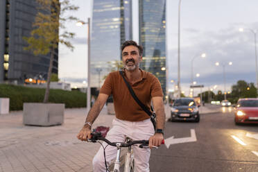 Lächelnder Pendler auf dem Fahrrad auf der Straße in der Stadt - JCCMF07600