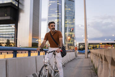 Geschäftsmann mit Fahrrad auf einem Fußweg in der Stadt - JCCMF07602