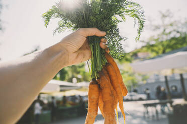 Frau hält einen Bund Karotten auf dem Markt - NDEF00003