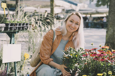 Lächelnde Frau bei blühenden Pflanzen auf dem Markt - NDEF00023