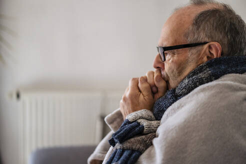 Älterer Mann in Decke eingewickelt friert zu Hause - DIGF19017