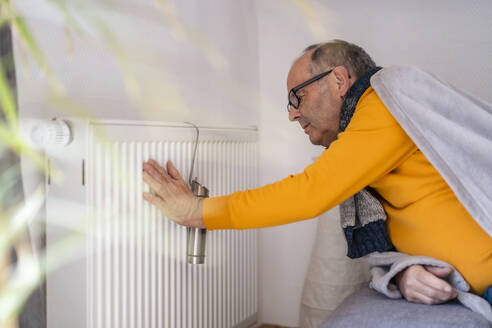 Senior man checking radiator temperature at home - DIGF19018