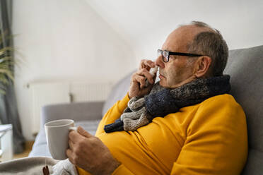 Älterer Mann benutzt Nasenspray auf dem Sofa zu Hause - DIGF19031