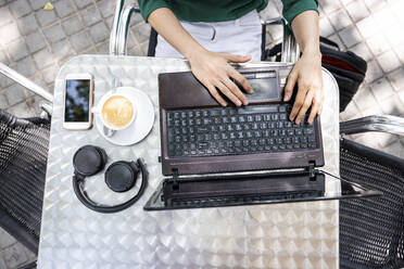 Freelancer working on laptop at sidewalk cafe - WPEF06555