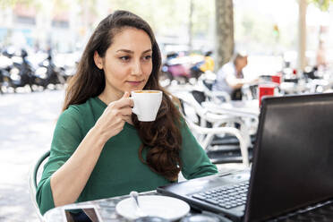 Freiberufler mit Kaffeetasse und Laptop in einem Straßencafé - WPEF06556