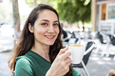 Glücklicher Freiberufler mit Kaffeetasse in einem Straßencafé - WPEF06558