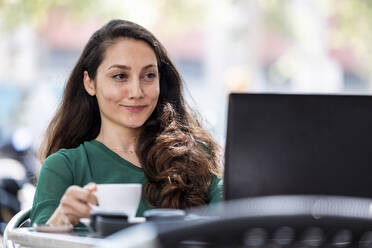 Lächelnder Freiberufler mit Laptop in einem Straßencafé - WPEF06562