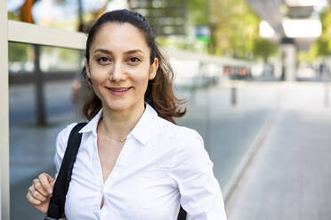 Happy businesswoman standing at footpath - WPEF06578