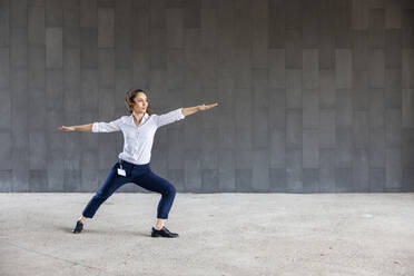 Woman practicing yoga in front of wall - WPEF06589