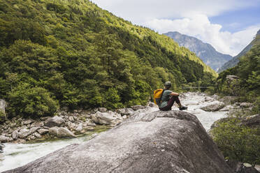 Mature woman sitting on rock in front of mountains - UUF27594