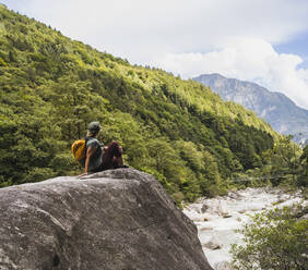 Woman sitting on rock in front of mountains - UUF27595