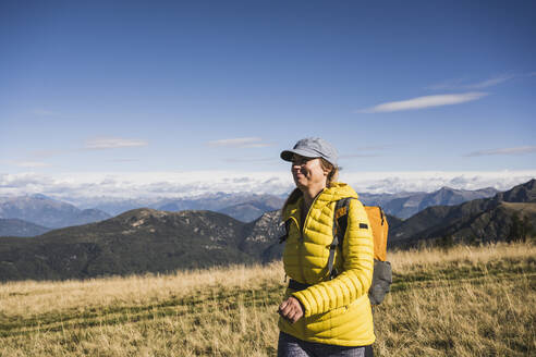 Lächelnde reife Frau beim Wandern an einem sonnigen Tag im Urlaub - UUF27627