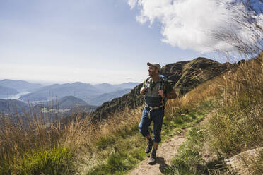 Mature man wearing cap hiking on mountain - UUF27634