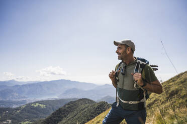 Happy mature man wearing cap standing on mountain under sky - UUF27640