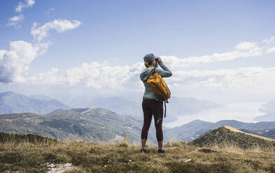 Woman photographing through camera in front of mountains - UUF27645
